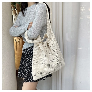 Close-up of beige crochet tote bag with geometric knit hollow pattern and wide shoulder strap