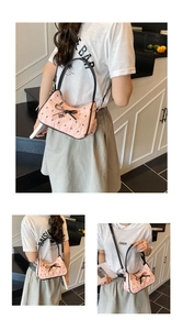 Close-up of pink quilted bag with letter patterns and a black bow with heart charm