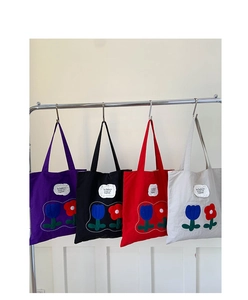 Close-up of canvas tote bags with tulip embroidery and minimalist text tags in four colors