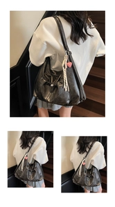 Detailed view of a black pleated tote bag with pink heart and tassel charms decoration