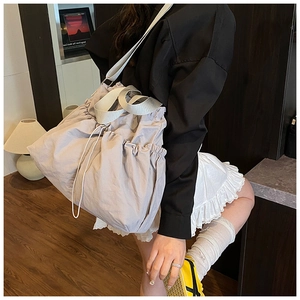 Lifestyle view of large lavender drawstring tote bag worn over the shoulder by a model