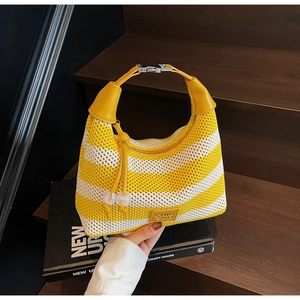 Detail of yellow and white striped knit bag with leather handle and fringe charm