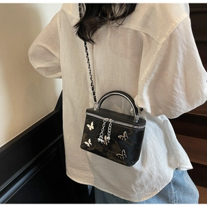 Fashionable black box bag with butterfly charms worn by a model in casual outfit