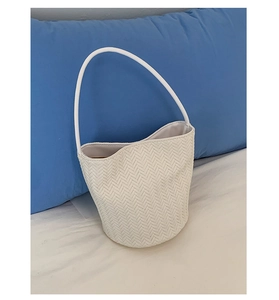 Detail view of white woven tote bag showing chevron texture and wavy edge design