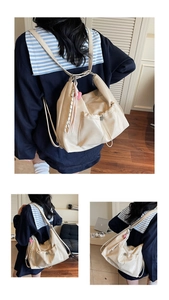 Detail view of cream pleated shoulder bag with heart charm and striped ribbon accent