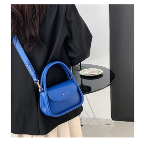 Detailed view of a blue leather mini square bag with detachable strap worn by a model