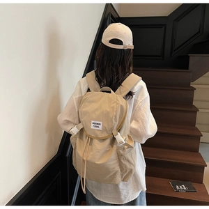 Sac à dos en toile kaki avec boucle et casquette assortie sur des marches d'escalier