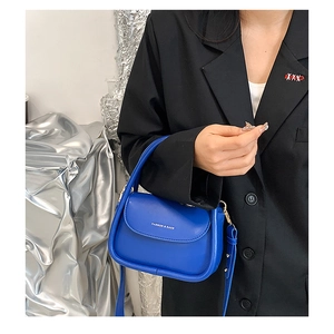 Detail of Klein Blue leather square bag with gold hardware and logo inscription