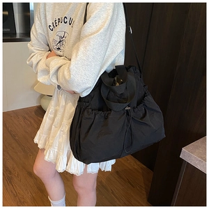 Detail of black nylon drawstring shoulder bag with pleated texture and wide strap
