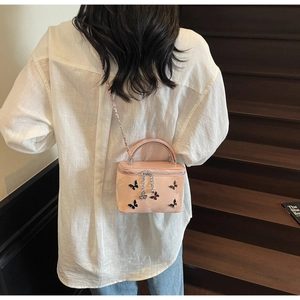 Close-up of pink box bag with butterfly decorations and dual zippers on wooden stairs