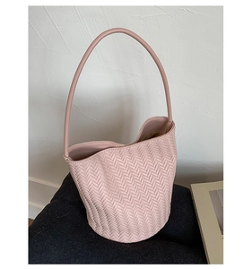 Detail of light pink woven bucket bag featuring refined herringbone texture and shoulder strap