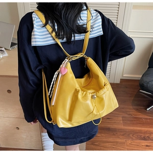 Rear view of model wearing a bright yellow pleated tote bag with a pink heart charm