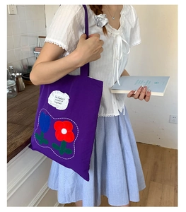 Detail of purple canvas tote bag with embroidered tulip patches and inspirational quote