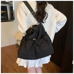 Lifestyle view of a large black drawstring canvas tote bag worn on the shoulder
