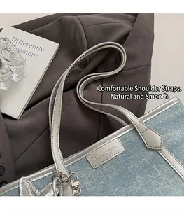 Close-up of a large denim tote bag with silver trim and stylish heart charm detail