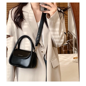 Detail of the black matte leather flap with white logo and adjustable shoulder strap