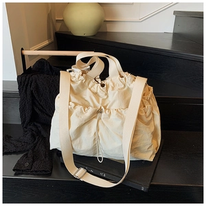 Detail of cream-colored drawstring canvas bag with adjustable wide shoulder strap on stairs