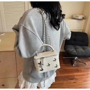 Chic cream box bag with silver butterflies shown in a minimalist interior setting