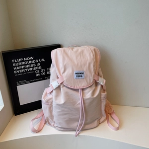 Détail d'un sac à dos rose clair en nylon imperméable avec fermoir et étiquette logo