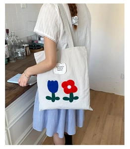 Detail of off-white canvas tote bag with floral prints and motivational text on the side