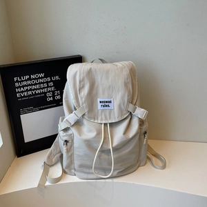 Détail du sac à dos en nylon blanc cassé montrant la boucle et l'étiquette en tissu