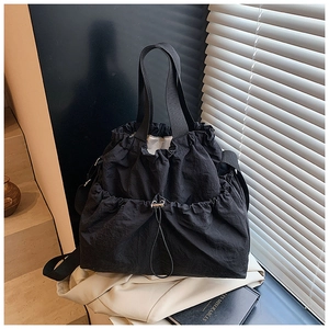 Detail of black drawstring tote bag showing the textured synthetic fiber and woven handles