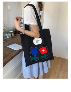 Detail of black canvas tote bag with floral patchwork and motivational quote patch