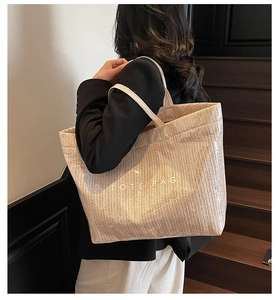 Detailed view of large woven tote bag with herringbone texture and TOTE BAG text print