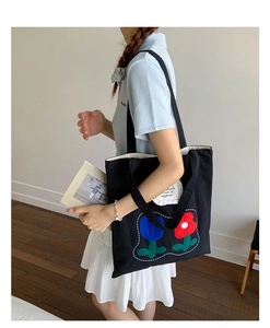 Close-up of black canvas tote bag featuring vibrant red and blue tulip floral embroidery