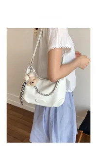 Detail of cream tote bag with lychee texture, silver chain and cute teddy bear pendant