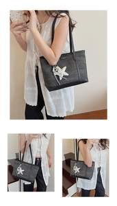 Detail of grey fabric tote bag with black leather trim, brand tag, and silver star charm
