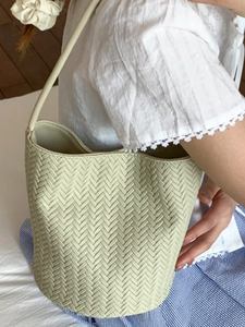 Minimalist light green woven bucket bag with slim shoulder strap for casual wear
