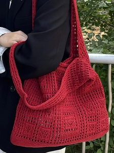 Red handmade crochet tote bag for summer beach use shown on a model in nature