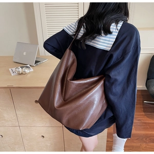 Brown soft leather tote bag detail with textured surface on a laptop workspace