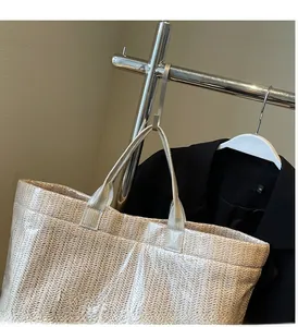Close-up of beige woven straw tote bag featuring herringbone texture and sturdy top handles