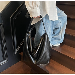 Detail view of slouchy black soft leather hobo bag with a zipper and long strap