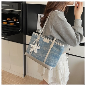 Side view of blue denim tote bag with silver leather trim and a star charm detail