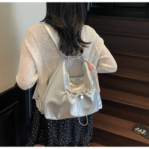 Detail of silver metallic slouchy bag featuring a drawstring closure and pink tassels