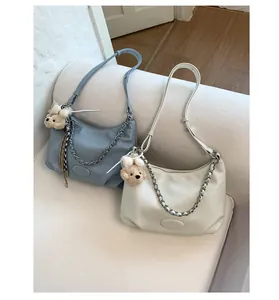Close-up of stylish PU leather tote bag with thick metal chain and teddy bear charm