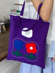 Fashionable purple canvas tote bag featuring floral tulip patches and a slogan for women