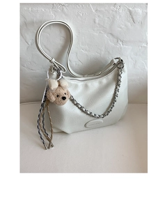 Detailed view of white textured leather tote bag with silver chain and cute bear charm