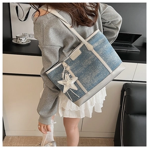 Detail of blue denim tote bag with leather patchwork and silver star charm