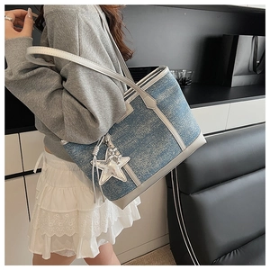 Detail view of large denim tote bag with silver sequin star pendant and long tassel
