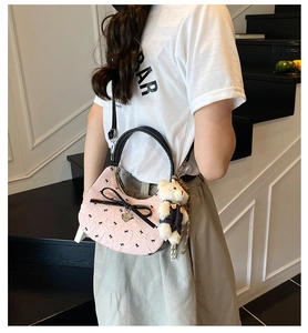 Détail du sac croissant rose avec nœuds noirs, pendentif ours et breloque cœur doré