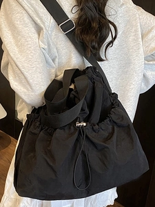 Minimalist black drawstring nylon tote bag with adjustable strap and side pockets