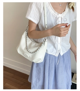 Detailed shot of white minimalist hobo bag featuring silver chain and leather strap