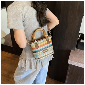 Detail of rainbow woven straw bag featuring vintage bamboo handles and brown leather strap