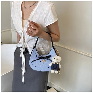 Détail d'un sac demi-lune rayé bleu clair avec nœud noir et charmant petit ours blanc