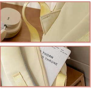 Macro detail of reinforced shoulder strap stitching and zipper on beige school backpack