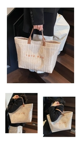 Detail of large beige woven tote bag with orange lettering on a wooden staircase